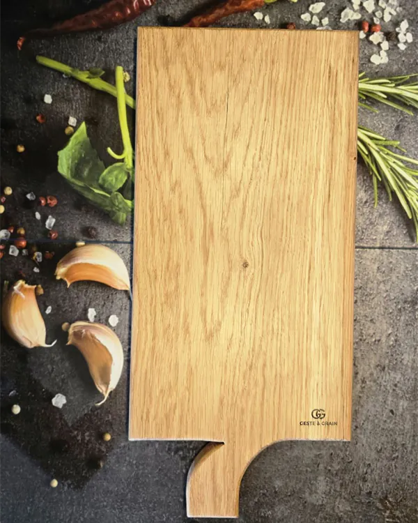 Planche de présentation à manche en bois massif, gravée Geste & Grain, posée sur un plan a, Geste & Grain